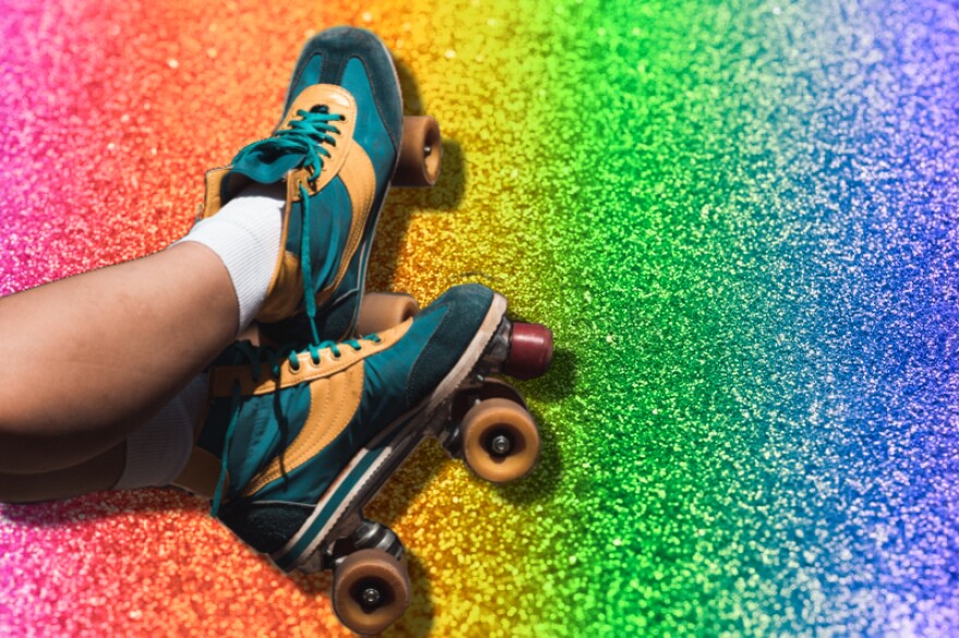A pair of legs in retro blue and yellow roller skates set against a sparkly rainbow background