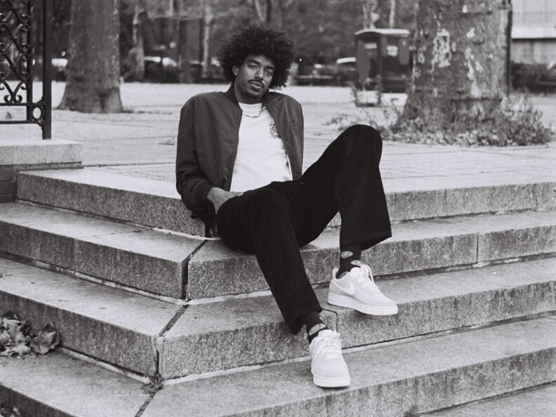 A black and white image of a man sitting on concrete steps.