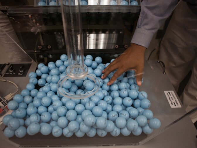 Vince McClure, a program analyst at the Selective Service, checks on balls marked with birthdates loaded into the draft lottery machine.