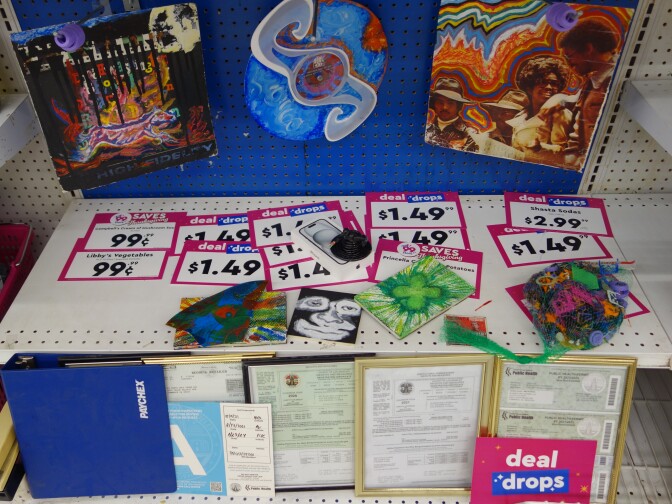 Cards showing discount prices appear on a store shelf with paintings and certificates of occupancy.