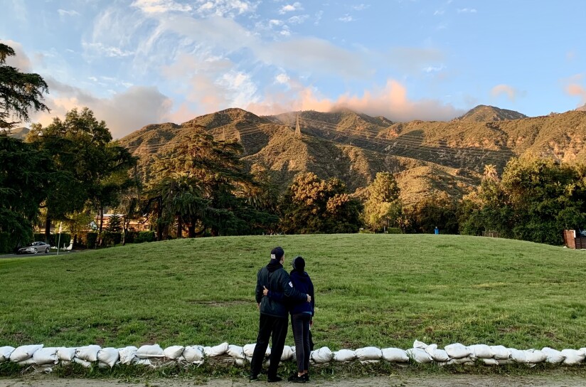 A couple, with their backs turned to the camera, look at the foothills surrounding Altadena. 