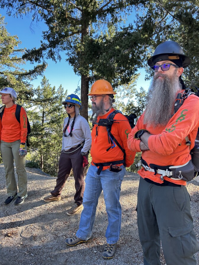 A vertical shot of four people wearing hardhats and bright shirts outside. 