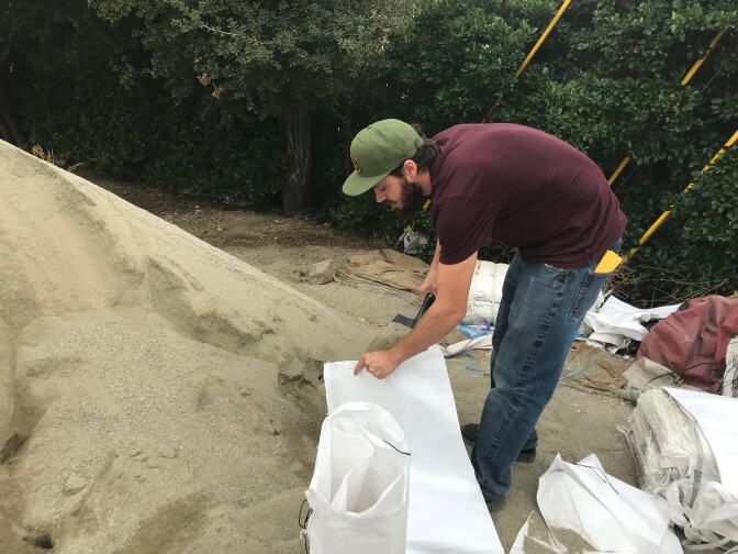Houston Waye fils a sandbag at Fire Station 65 in Agoura Hills. He's bringing sandbags to his neighbors in Seminole Springs, where over 100 homes were destroyed in the fires. (Photo by Emily Dugdale/KPCC)
