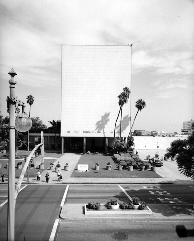 Located at 150 N. Los Angeles Street, the Police Administration Building served as the headquarters for the LAPD from 1955 to 2009. Designed by Welton Becket in association with J. E. Stanton and landscape architect Ralph D. Cornell, the 7-story, Modernist structure includes a horizontal slab with bands of windows on the long east and west sides, and glazed terra cotta panels on the short north and south sides. Horizontal 2-story wings extend out into the surrounding parking lots, defining an entrance plaza and a visual base for the building. The design of the entrance plaza and gardens was part of the Modern landscape architecture trend to unite indoor and outdoor space. After the sudden death of Police Chief William H. Parker on July 16, 1966, the building was renamed Parker Center. 