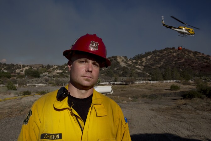 Captain Ryan Johnston of the United States Forest Service stands by as a helicopter replenishes its water supply at the Hillside Community Church in Wrightwood, California on August 18th, 2016.