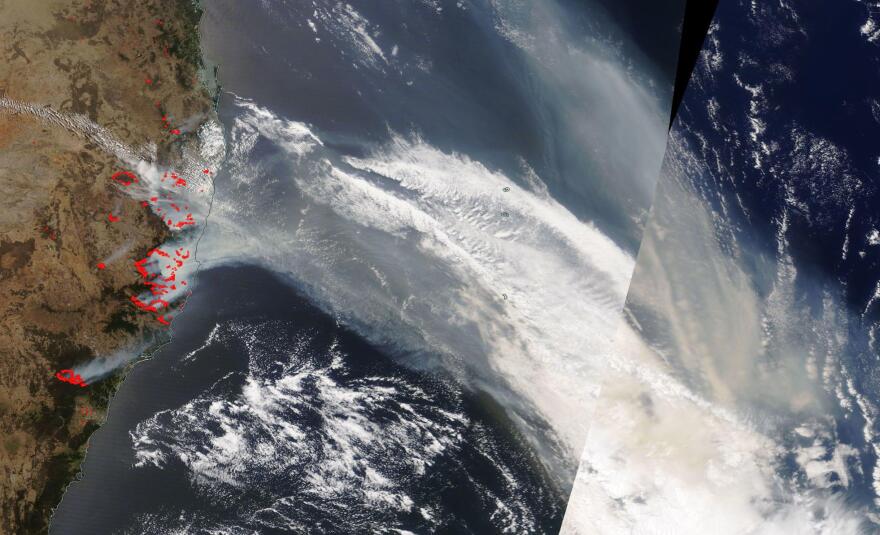 Red dots mark dozens of fires as large wafts of smoke are seen drifting over the ocean on a satellite image.