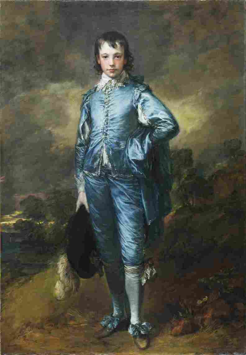 A young white man in a light blue coat and trousers in 18th century style stands with his hand on his hip.