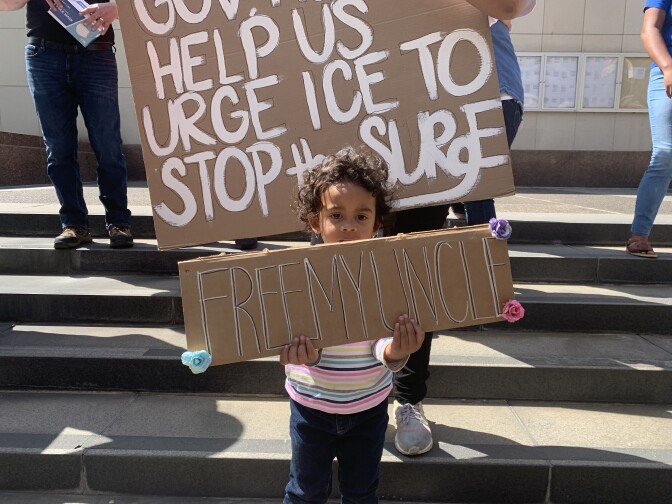 A 2.5 year-old girl holds a sign that reads "Free My Uncle."