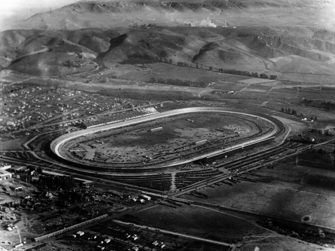 1924 "aerial view of the Culver City Speedway, which was in existence as an auto racing venue from December 14, 1924, until March 6, 1927. The large, gray, slanted structure on the left of the racetrack is the grandstand, and another one appears to be directly across on the other side. Hundreds of homes are visible past the racetrack, scattered throughout the city."