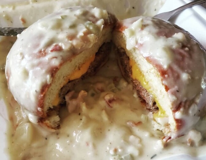 A close up of a cheeseburger sitting in the middle of a bowl, and covered in a white chunky substance  