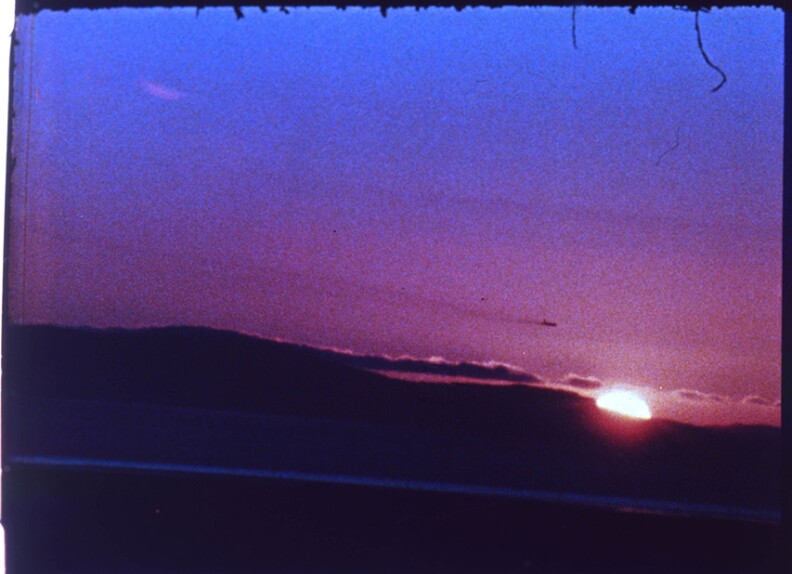A striking pink and blue sky, with the sun peeking out behind a darkened horizon