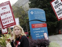 Nurse Kim Conklin holds up a sign as protests with other nurses outside of Alta Bates Medical Center in Berkeley, Calif., Thursday, Sept. 22, 2011. Nurses began picketing Thursday morning outside dozens of Northern and Central California hospitals as part of a one-day strike over benefit cuts and other concessions sought by hospital management. (AP Photo/Jeff Chiu)