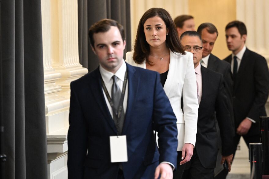 Cassidy Hutchinson, in a white blazer, is escorted to the hearing.