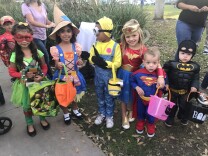 several children are dressed in Halloween costumes including Teenage Mutant Ninja Turtle, scarecrow, minion, Wonder Woman, Superman and Batman 