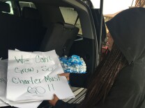 Maisha Riley, school leader at Community Preparatory Academy, a charter school, pulls from her trunk a stack of protest signs left along the fence of the L.A. Unified campus in Carson where they're co-located.
