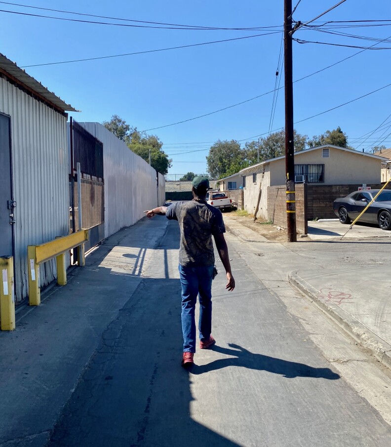 Tryron Ramsey is walking down an alley and pointing to a wall where he says he would sometimes sit with his suitcase before moving into a shelter.