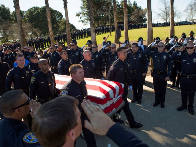 Riverside Police Officers salute Michael Crain's coffin at the Riverside National Cemetery. Crain was shot dead by Christopher Dorner on February 7th, 2013.