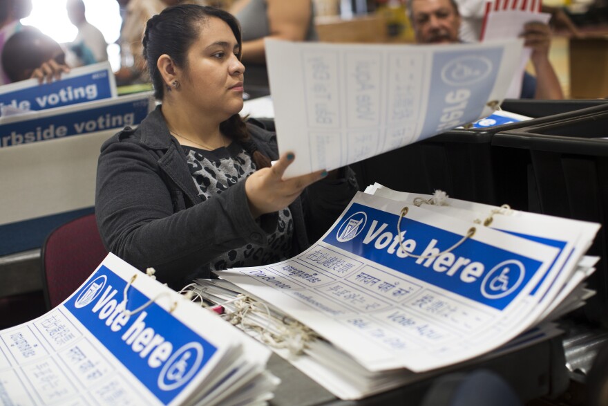 Joana Briones places "Vote here" signs into supply tubs on Thursday, Oct. 23, 2014 at Los Angeles County's Elections Operations Center in Santa Fe Springs. The tubs will be distributed to thousands of voting precincts in L.A. County for the Election Day.