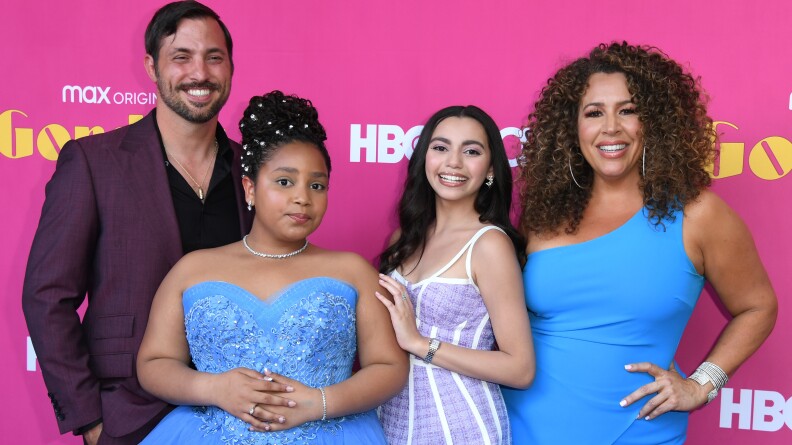Four people in dress clothes pose in front of a pink backdrop that touts HBO Max and the Gordita Chronicles.