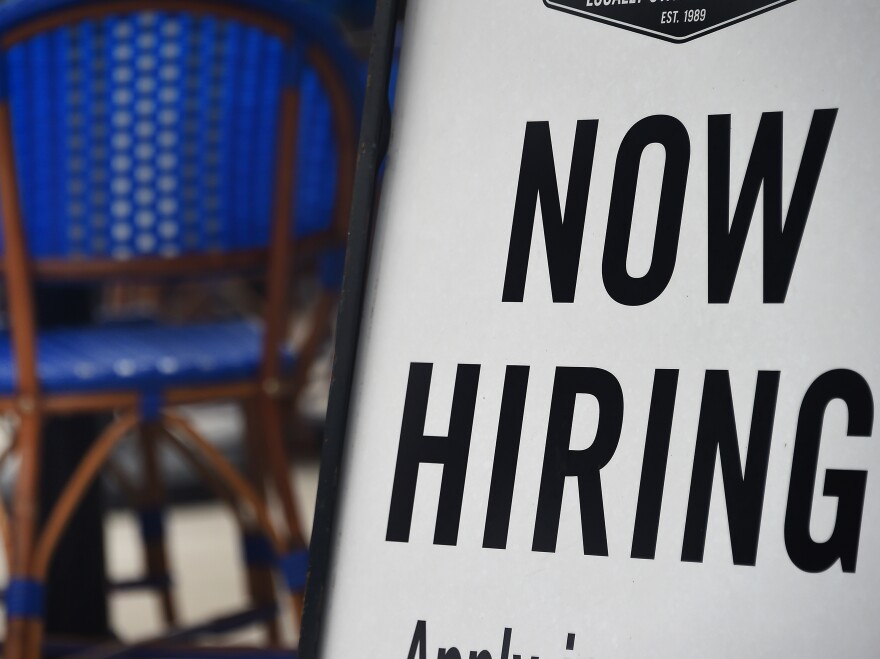 A restaurant displays a "Now Hiring" sign.