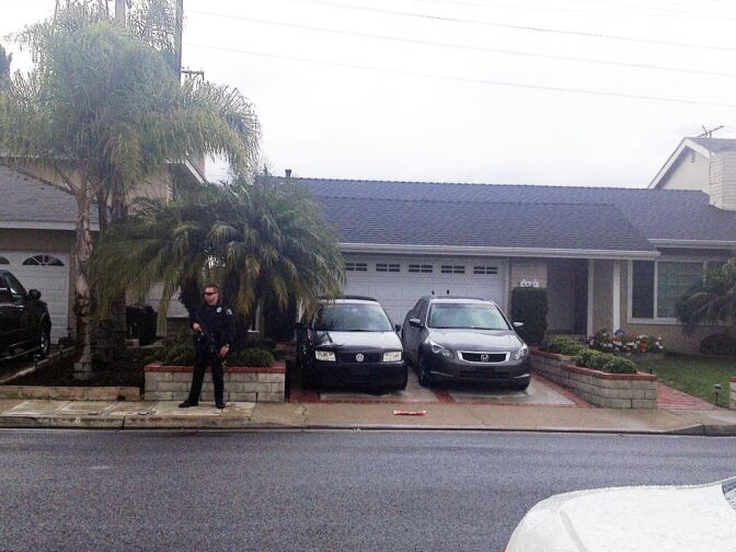 An officer stands guard outside Christopher Dorner's La Palma home as authorities carry out a search warrant on Friday morning.