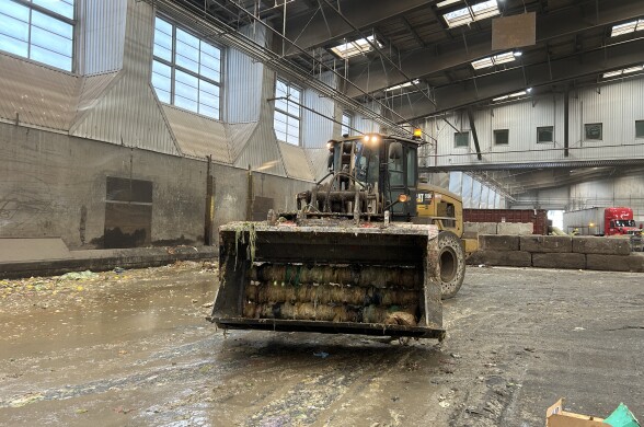 A frontloader faces the camera in a large warehouse. 