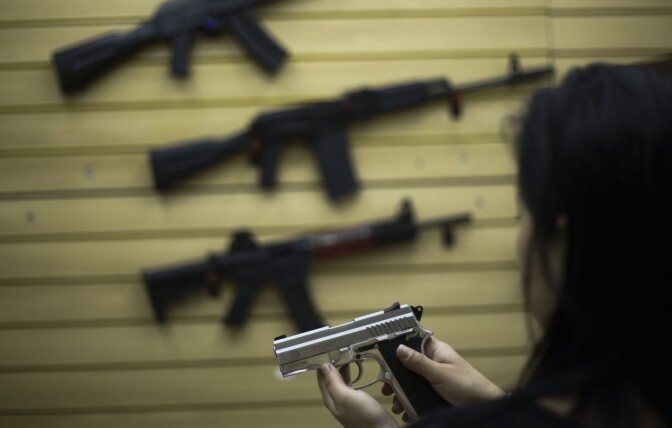 File: A woman handles a pistol at a gun shop.