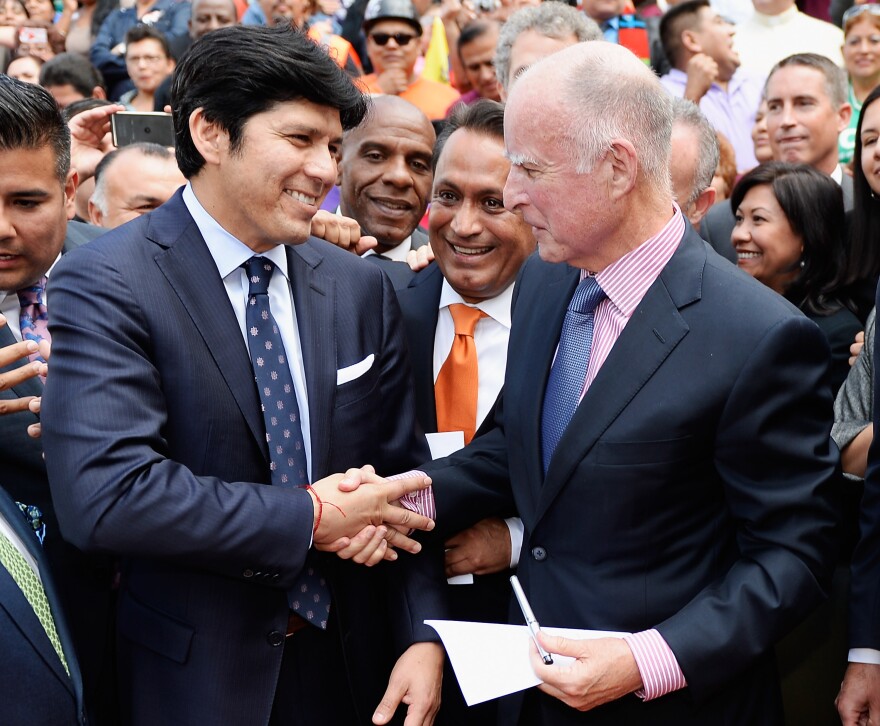 LOS ANGELES, CA - OCTOBER 03:  California Governor Jerry Brown (R) celebrates with Democratic State Senator Kevin de Leon (L) and Los Angeles councilman Gil Cedillo (C) after signing bill AB60 on the steps of Los Angeles City Hall October 3, 2013 in Los Angeles, California. California Assembly Bill 60 also known as the Safe and Responsible Driver Act allows illegal immigrants to receive a permit to legally drive in California.  (Photo by Kevork Djansezian/Getty Images)