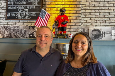 Thomas Crijns and his wife, Carol, at Brussels Bistro in San Clemente. The Manneken-Pis statue behind them, dressed in a Belgian national team jersey, is one of the restaurant's many nods to the World Cup.