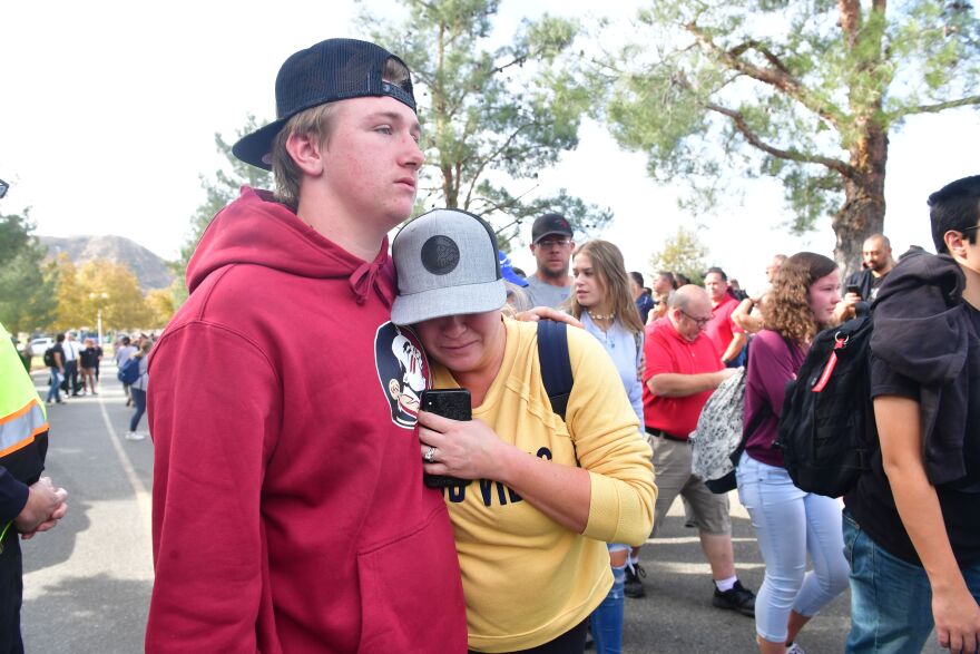 People react near Central Park after a shooting at Saugus High School in Santa Clarita, California on November 14, 2019. - At least four people were injured in a shooting at a high school north of Los Angeles Thursday, triggering a police hunt for the suspect who was later taken into custody.One female was killed Thursday, hospital officials said. The suspect was in custody and taken to a hospital for treatment, while at least three others were injured in the shooting at Saugus High School in Santa Clarita, 40 miles (65 kilometers) north of Los Angeles."One female deceased patient. Two critical male patients. One male patient in good condition," tweeted the nearby Henry Mayo Hospital in Valencia.No further details of the deceased were provided. (Photo by Frederic J. BROWN / AFP) (Photo by FREDERIC J. BROWN/AFP via Getty Images)