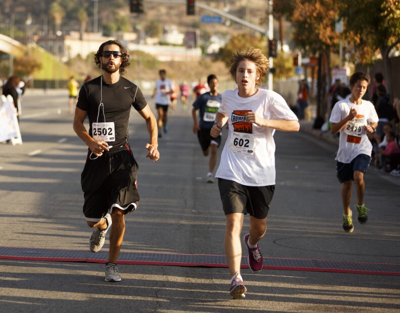 Three runners prepare to cross the finish line of an outdoor race.