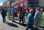 A group of people stand in a parking next to a red food truck