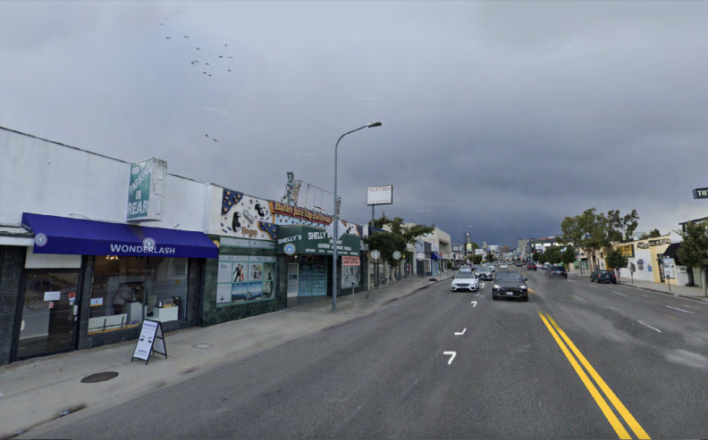 A Google image of a wide, paved street with low buildings and overcast sky.