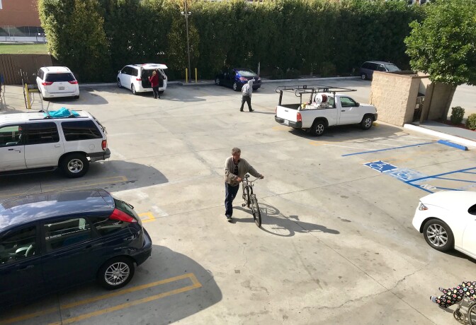 Fritz Reichenbach pushes his bicycle across the parking lot of the Buena Park motel he's staying at.
