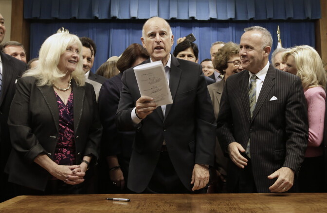 Gov. Jerry Brown holds up the measure he signed to  place a $7.5 billion water plan on the November ballot, Wednesday, Aug. 13, 2014, in Sacramento, Calif.  The measure replaces an existing water bond that was approved by a previous Legislature but was widely considered to costly and unlikely to be approved by voters. The water plan was approved by lawmakers earlier in the day after weeks of negotiations between Brown and legislative leaders.  Also seen are Assembly Minority Leader Connie Conway, R-Tulare, left,and Senate President Pro Tem Darrell Steinberg, D-Sacramento, right. (AP Photo/Rich Pedroncelli)