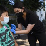Jair Flores, 12, closes their eyes as they receive a first dose of the Pfizer Covid-19 vaccine at a mobile vaccination clinic at the Weingart East Los Angeles YMCA on May 14, 2021 in Los Angeles, California. - The campaign to immunize America's 17 million adolescents aged 12-to-15 kicked off in full force on May 13. The YMCA of Metropolitan Los Angeles is working to overcome vaccine hesitancy and expand access in high risk communities with community vaccine clinics in the area. (Photo by Patrick T. FALLON / AFP) (Photo by PATRICK T. FALLON/AFP via Getty Images)