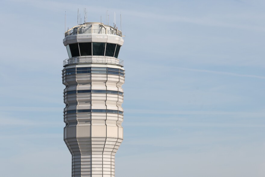 A tall air traffic control tower. At the top is a circular room with windows on all sides