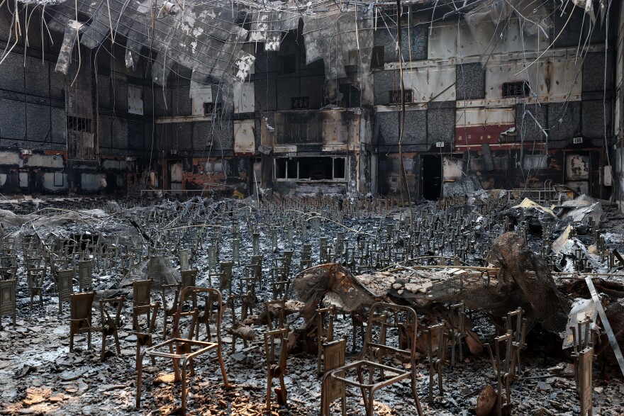 The interior of a large auditorium scorched from a fire. The metal frames of chairs remain.