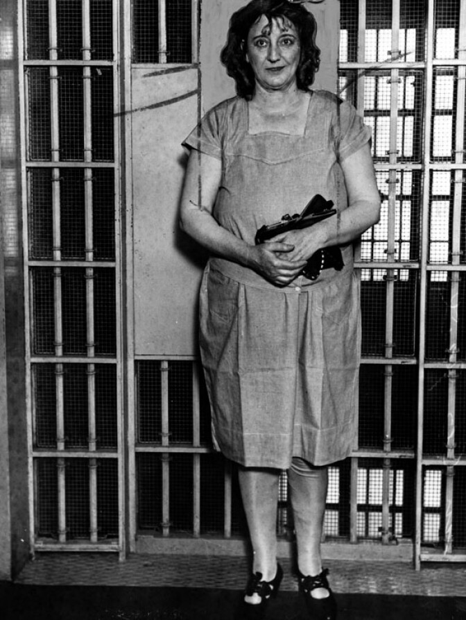 Mrs. Walburga Oesterreich standing in front of a jail cell. 