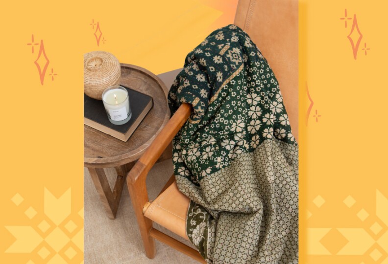 A quilt is draped over a chair next to small wood table
