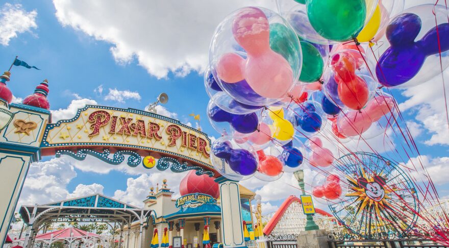 The Pixar Pier arch, with Mickey Mouse balloons in front of the ferris wheel.