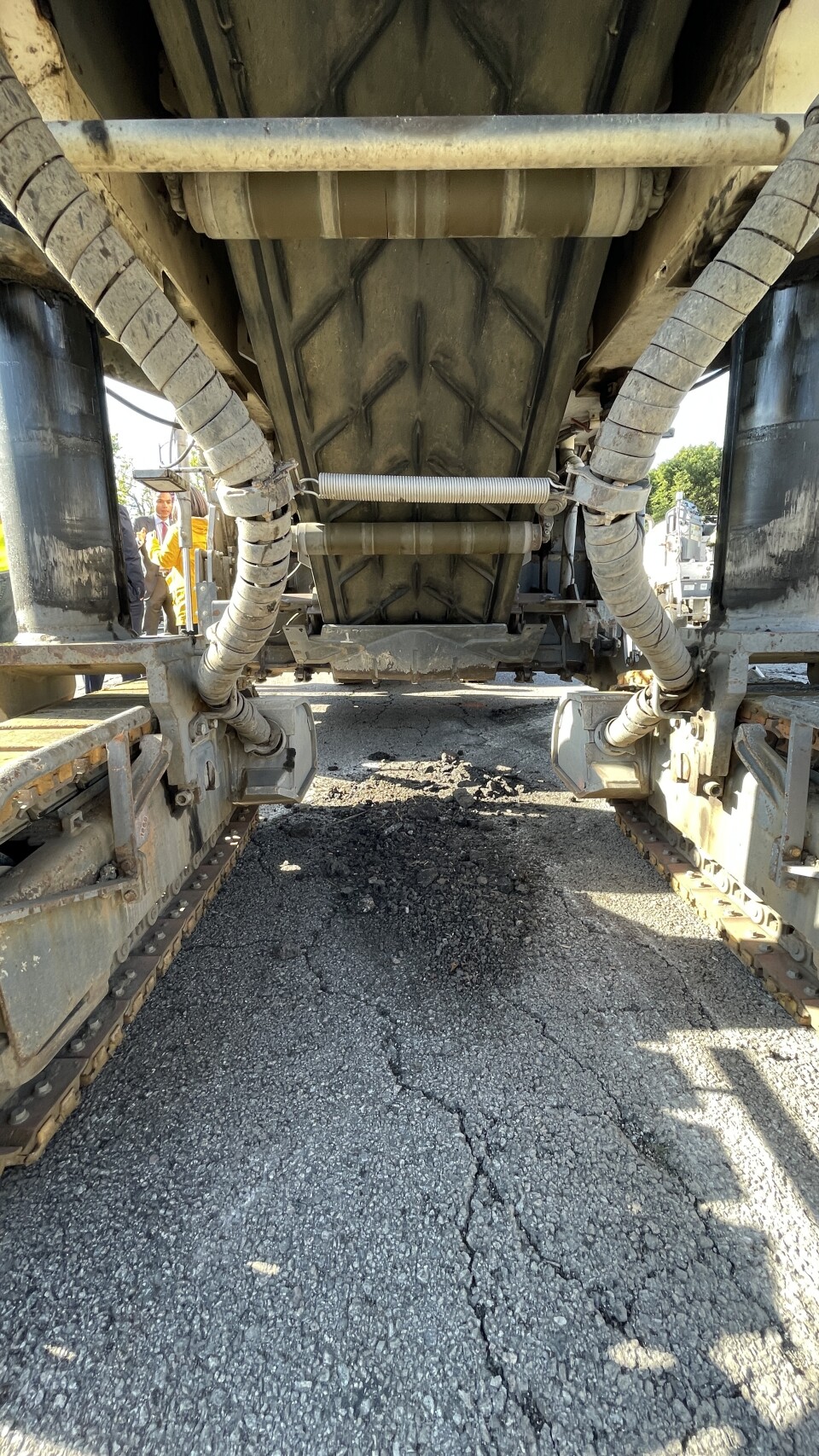 An image showing beneath a machine with some sort of conveyer belt that helps shunt away road debris as it's ground down.