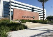 The exterior of a building has a terra cotta-colored stone wall with the words : County of Orange Civic Center and the seal of Orange County.