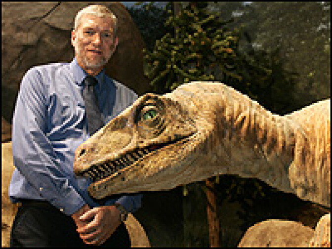 Ken Ham poses with a mechanical Utahraptor at The Creation Museum.