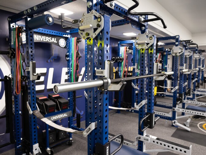 A gym room boasts top-of-the-line equipment, including numerous stations where you bench presses and pull ups are carefully monitored and documents.