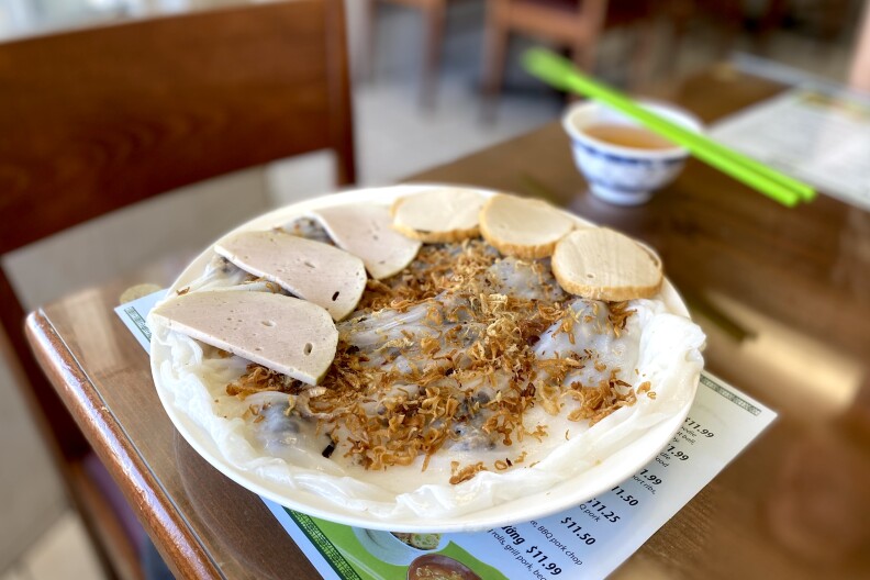 A plate of food with a thin translucent rice cake topped with fried shallots and surrounded by meat.