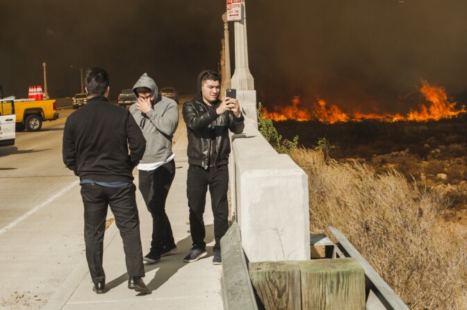 People take photos on their cell phones at the edge of the Creek Fire in Lakeview Terrace on Dec. 5, 2017.