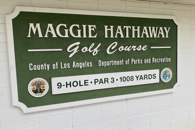 A sign in white lettering on a green background says "Maggie Hathaway golf course - county of Los Angeles - Department of Parks and Recreation." At the bottom of the sign in black lettering on a white background it says, "9-hole par 3 - 1,008 yards."