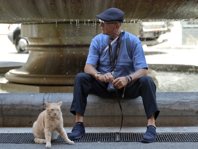 A man sits near a fountain and keeps his cat on a lead on May 25, 2012 in Rome.