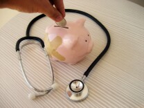 A piggy bank with a ban aid on it and a stethoscope